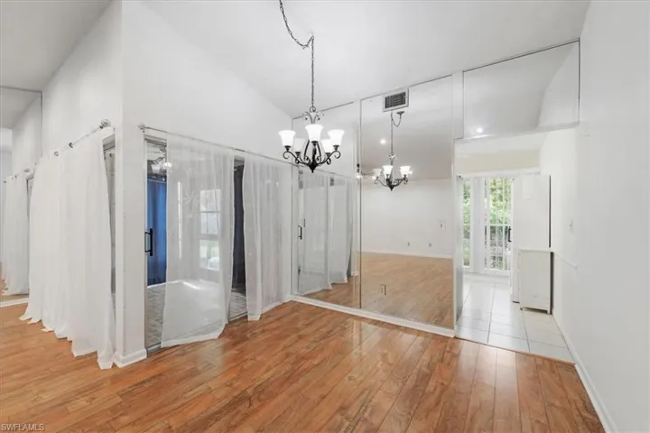 Unfurnished dining area with a notable chandelier, high vaulted ceiling, and light tile floors