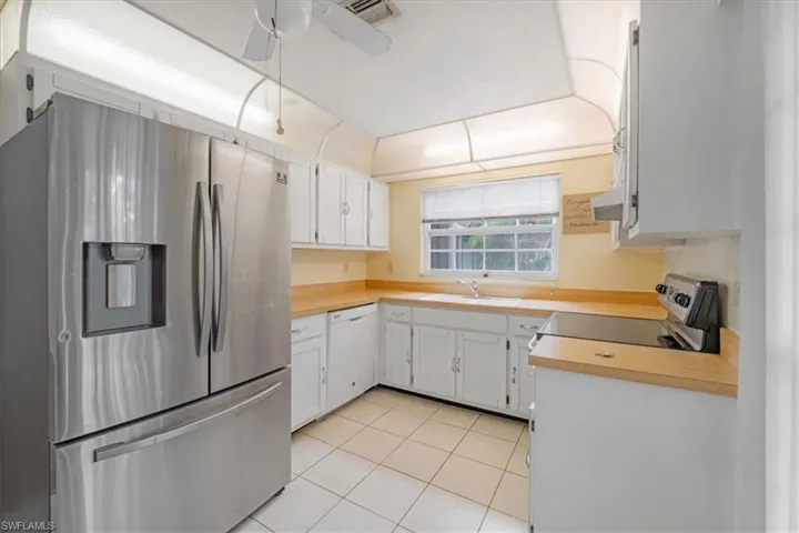 Kitchen featuring ceiling fan, light tile flooring, sink, white cabinetry, and appliances with stainless steel finishes