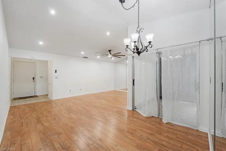 Unfurnished dining area with light wood-type flooring and ceiling fan with notable chandelier