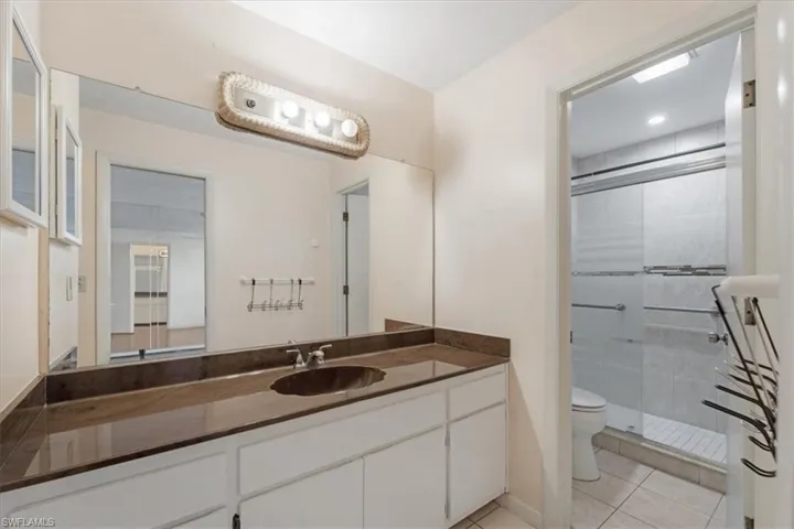 Bathroom with vanity, toilet, tile floors, and a shower with door