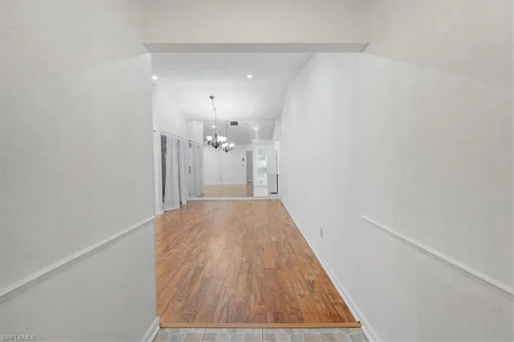 Corridor with a notable chandelier and hardwood / wood-style floors