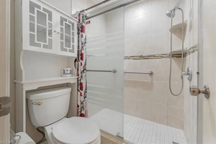 Bathroom featuring tiled shower and toilet