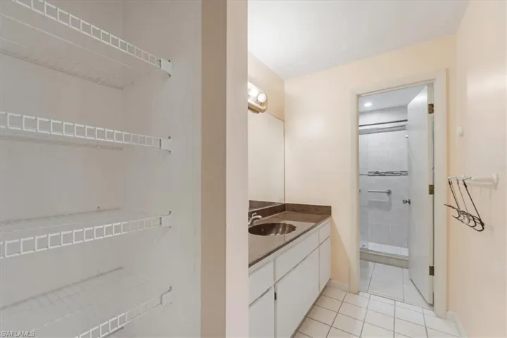 Bathroom featuring vanity with extensive cabinet space, walk in shower, and tile floors