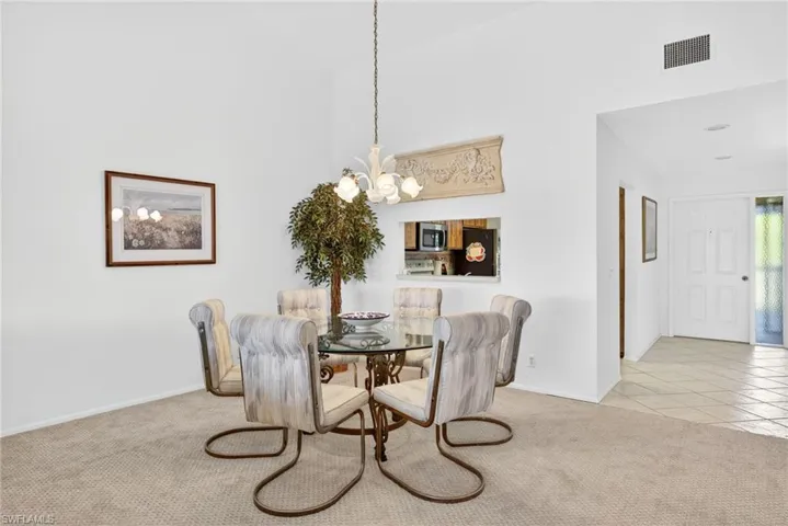 Dining area featuring light colored carpet, a chandelier, light tile patterned floors, and a high ceiling
