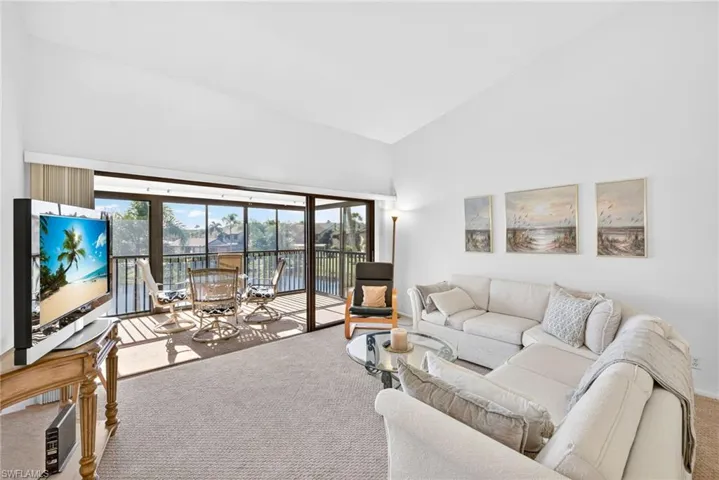 Living room with carpet floors, a water view, and high vaulted ceiling