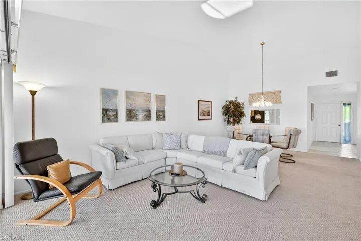 Carpeted living area featuring high vaulted ceiling and a chandelier