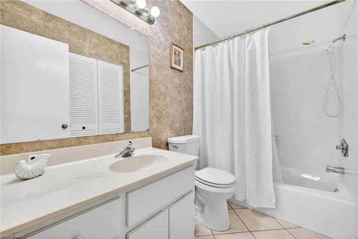 Bathroom with light tile patterned flooring, vanity, shower / bath combo, and a closet