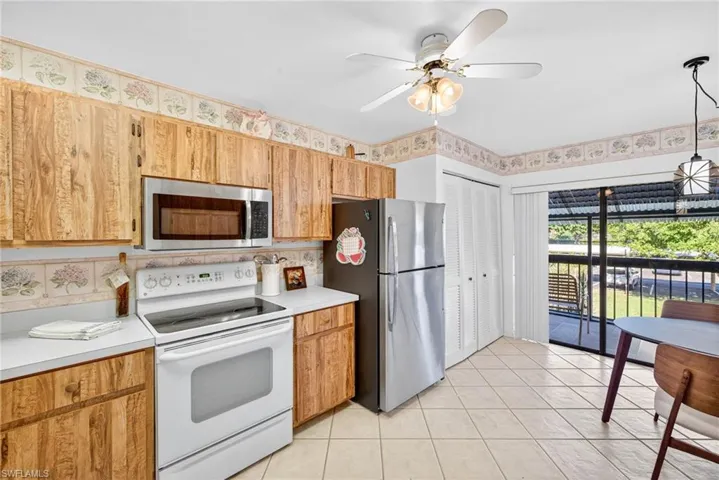 Kitchen with appliances with stainless steel finishes, light countertops, light tile patterned floors, and brown cabinets