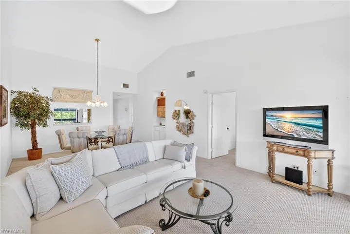 Living room featuring high vaulted ceiling, carpet flooring, and a chandelier