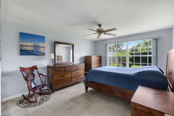 Spacious room featuring large gridded windows, tile flooring, and a ceiling fan