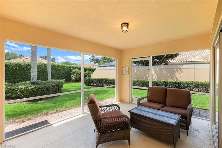 Screened patio featuring a ceiling-mounted light fixture, concrete flooring, and an expansive lawn beyond