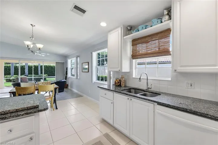 Kitchen featuring white shaker-style cabinetry, dark speckled countertops, and a double basin stainless steel sink with a high-arch faucet