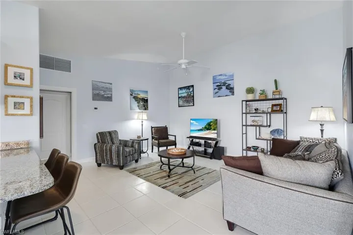 Expansive living area featuring light-toned tile flooring throughout and a vaulted ceiling with a ceiling fan