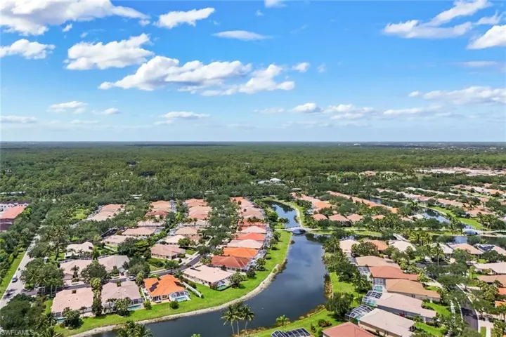 Residential development featuring a winding waterway with multiple bridges, surrounded by mature trees and manicured landscaping