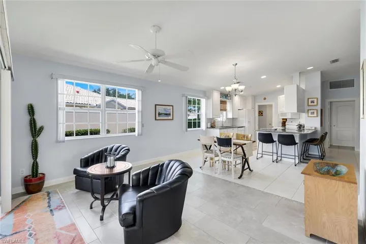 Open-concept living area featuring light-toned tile flooring, a multi-pane window, and a ceiling fan