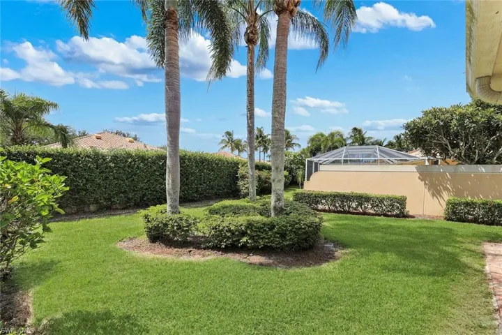 Expansive green lawn with mature palm trees and manicured hedges