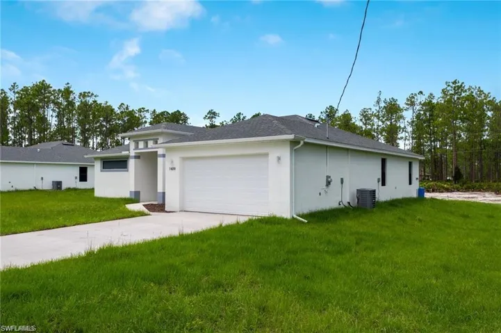 View of front of house featuring a garage, central air condition unit, and a front lawn