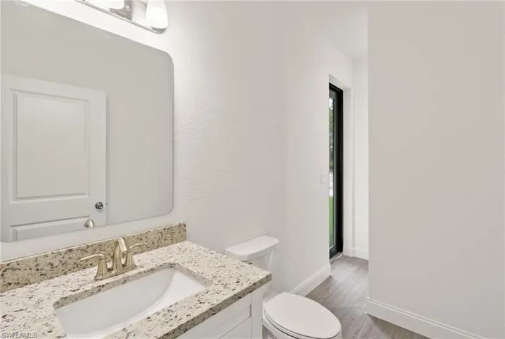 Bathroom with vanity, wood-type flooring, and toilet