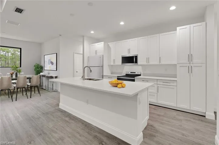 Kitchen featuring white cabinets, a kitchen island with sink, light hardwood / wood-style floors, appliances with stainless steel finishes, and sink