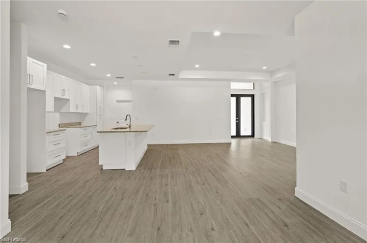 Kitchen featuring light hardwood / wood-style flooring, white cabinets, and a center island with sink