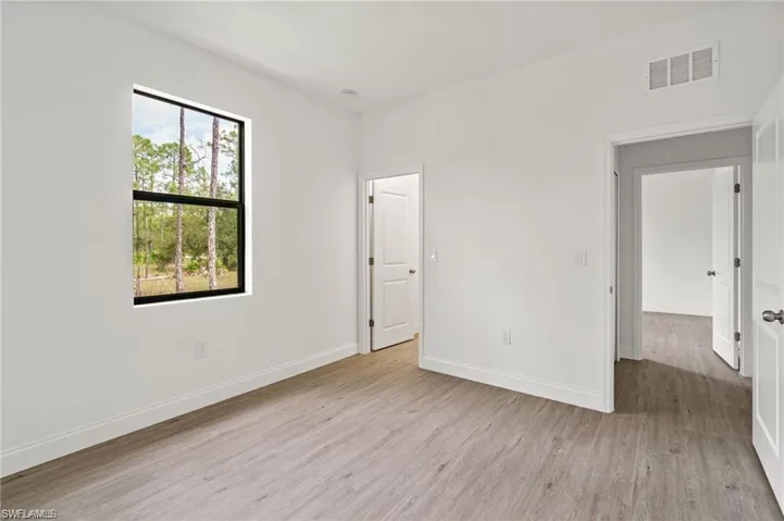 Unfurnished bedroom with multiple windows and light wood-type flooring