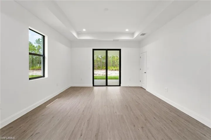 Spare room featuring wood-type flooring and a raised ceiling