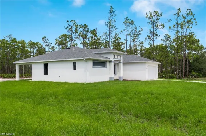 Back of property featuring a garage and a yard