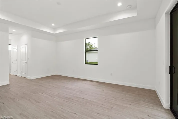 Unfurnished room featuring light hardwood / wood-style flooring and a tray ceiling