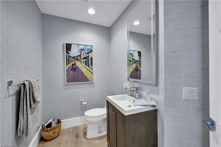 Charming powder room with custom vanity, lighting and wallpaper.