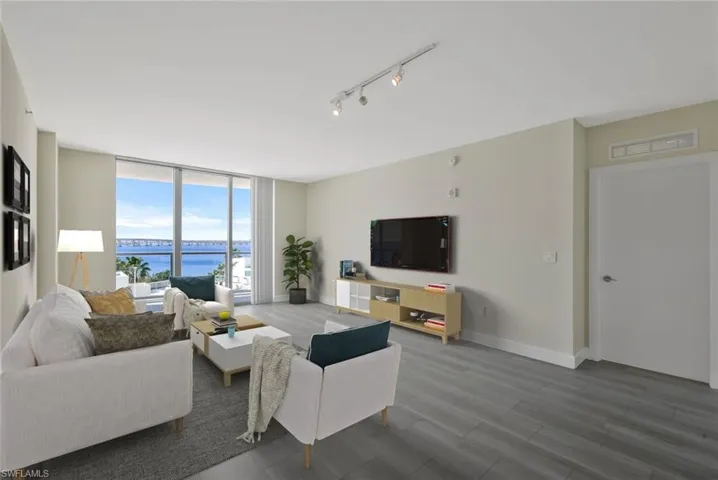 Open plan Living room with a wall of windows, large balcony with river and pool deck views, luxury vinyl flooring wood-type flooring - virtual staged
