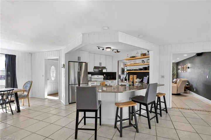 Kitchen featuring a kitchen breakfast bar, freestanding refrigerator, white range with electric cooktop, dark stone counters, and white cabinets