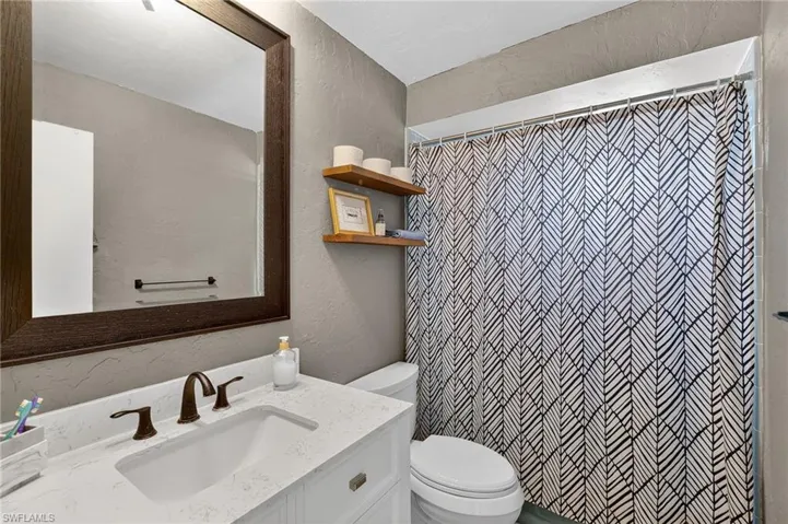 Bathroom with a textured wall, vanity, and a shower with curtain