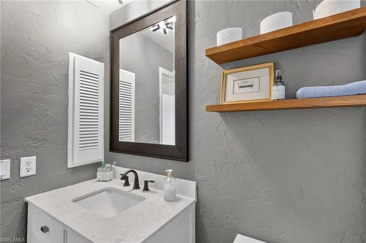 Bathroom featuring a textured wall and vanity