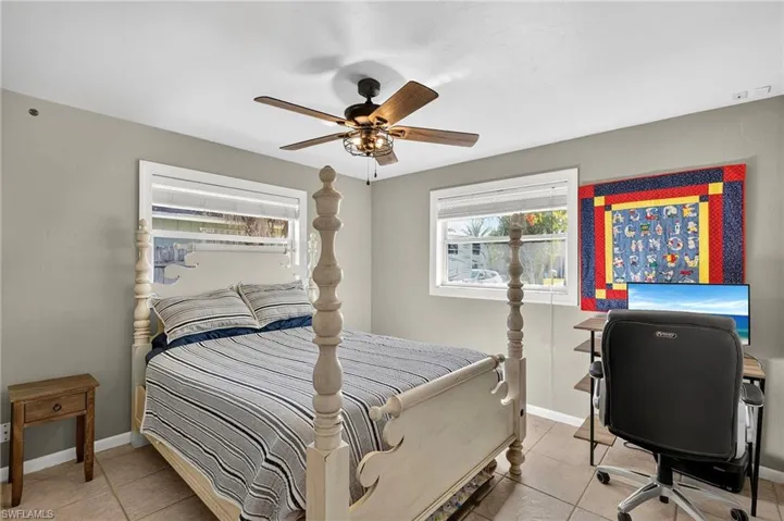 Bedroom featuring light tile patterned flooring, ceiling fan, and an office area