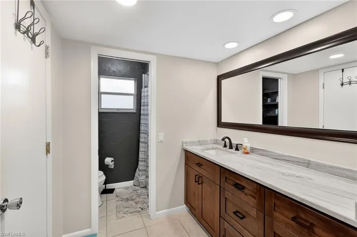 Full bathroom featuring curtained shower, vanity, light tile patterned flooring, and recessed lighting