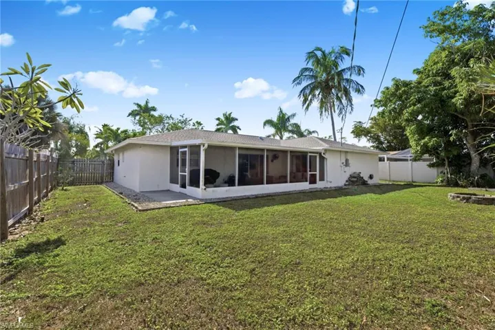Rear view of property with a fenced backyard, a sunroom, and stucco siding
