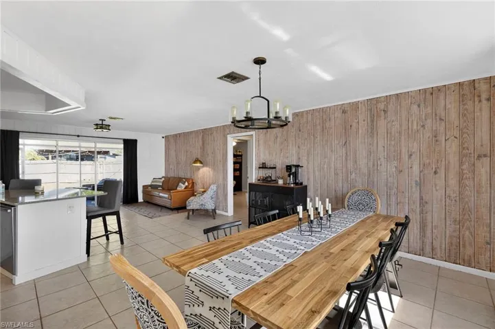 Dining space featuring wooden walls, light tile patterned floors, and a chandelier