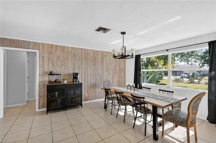 Dining room with wooden walls, light tile patterned floors, and a chandelier