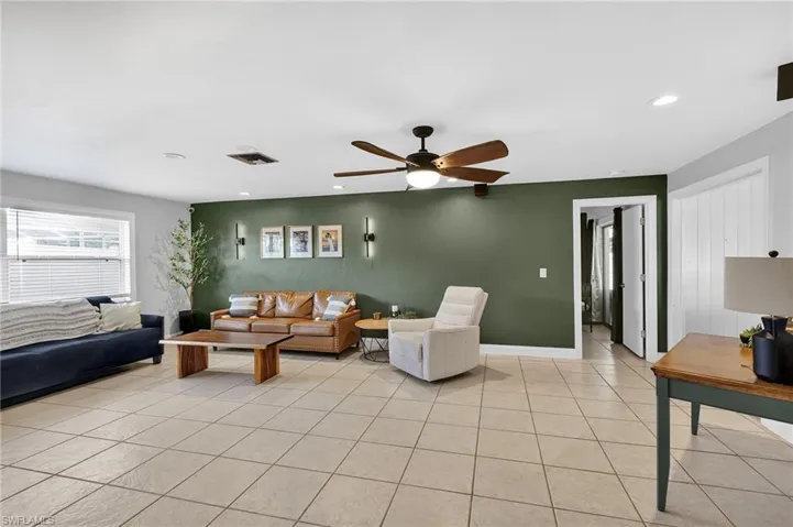 Living room with an accent wall, recessed lighting, ceiling fan, and light tile patterned floors