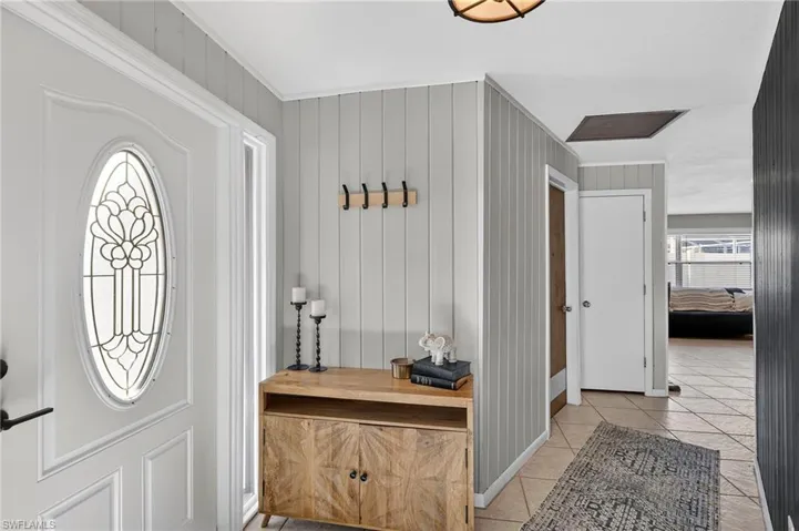 Entryway featuring light tile patterned floors and wooden walls