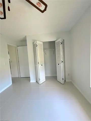 Unfurnished bedroom featuring a textured ceiling, light tile patterned floors, and a closet