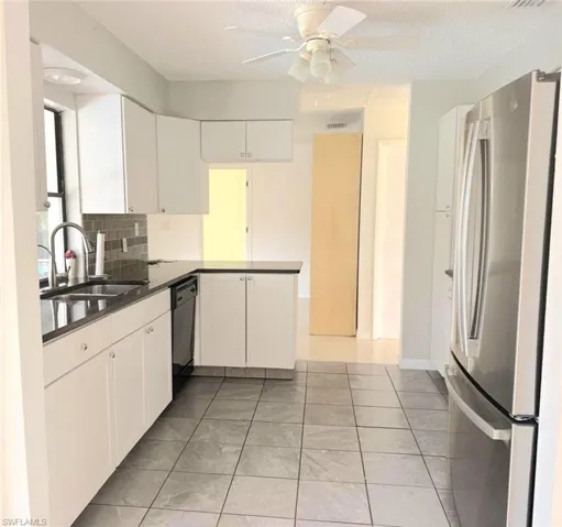 Kitchen featuring freestanding refrigerator, light tile patterned flooring, white cabinetry, a peninsula, and a textured ceiling