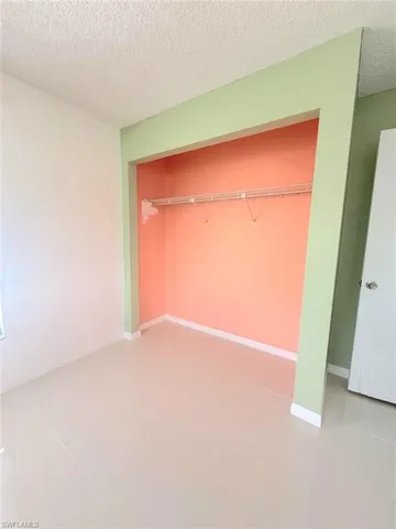 Unfurnished bedroom featuring a textured ceiling, light tile patterned floors, and a closet