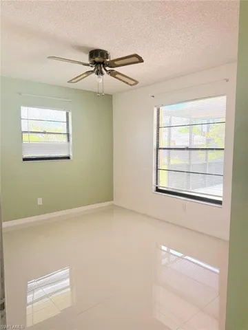 Tiled empty room with a textured ceiling and ceiling fan