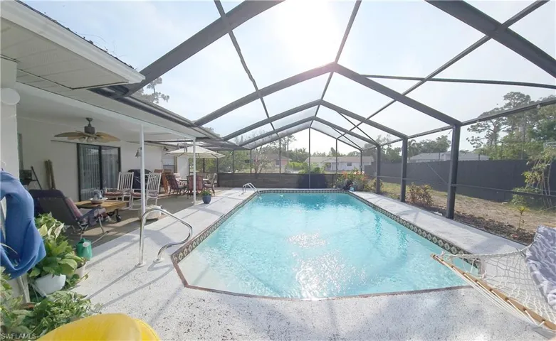 Swimming pool with a patio, a ceiling fan, outdoor dining area, a lanai, and fence