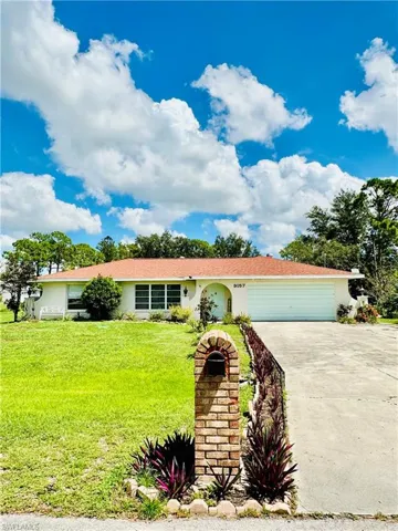 Ranch-style house featuring stucco siding, driveway, an attached garage, and a front lawn