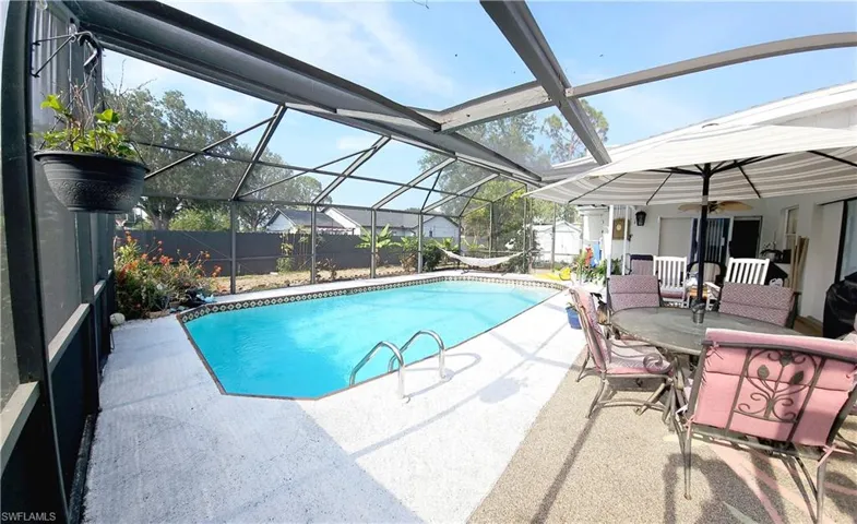 Swimming pool with a patio, a fenced backyard, a shed, an outbuilding, and glass enclosure