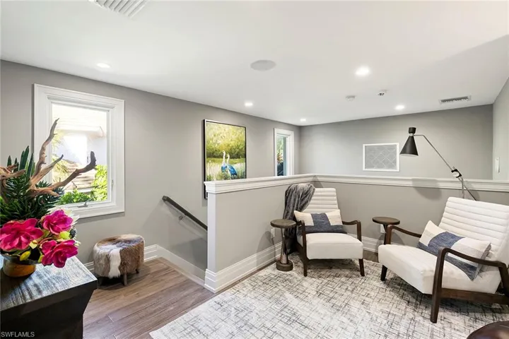 Living area with an upstairs landing, light wood finished floors, and recessed lighting