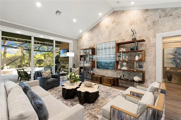 Living area featuring vaulted ceiling, wood finished floors, a sunroom, and recessed lighting