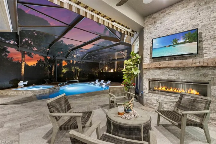 Integrated pool / spa with an outdoor stone fireplace, a patio, glass enclosure, and a sunroom